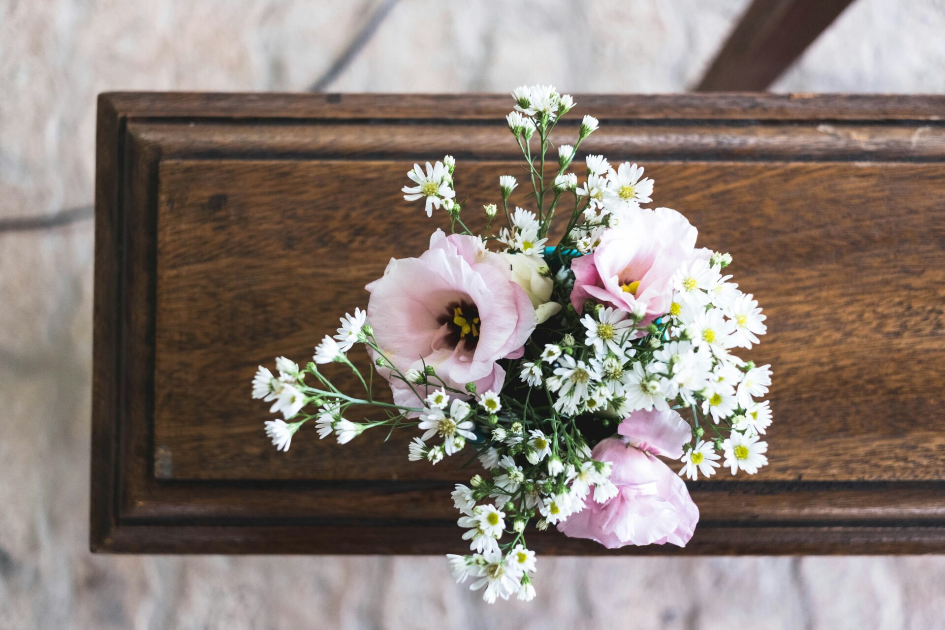 A top down view of a posy with pink flower and daisies.