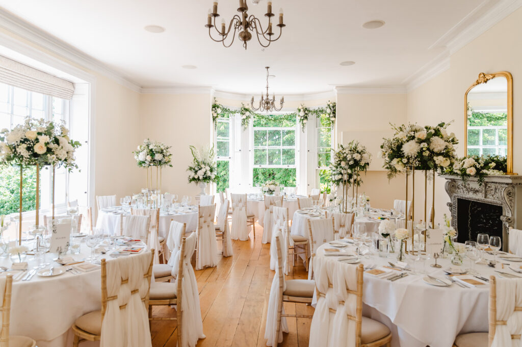 An ornate wedding reception room with floral arrangements and tall windows.