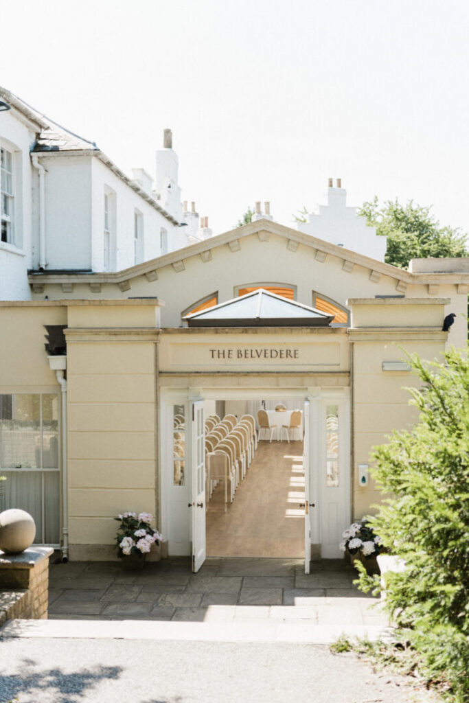 An exterior view of The Belvedere with doors open offering a view of rows of chairs inside.