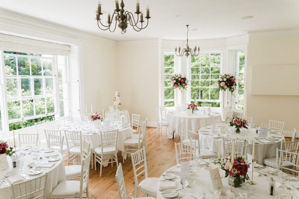 A wedding reception space with white tables and chairs with bright flower arrangements.