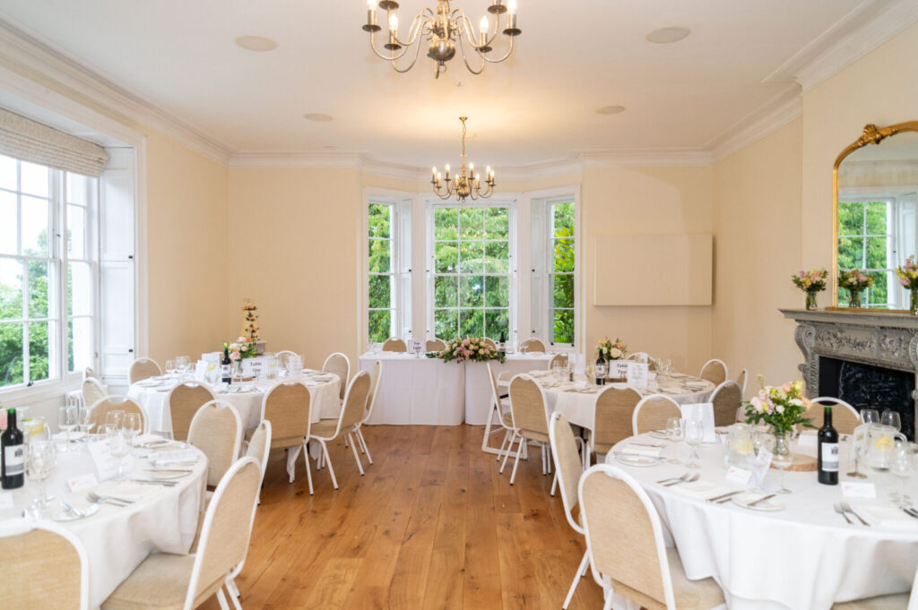 A warmly lit wedding reception room with set tables.