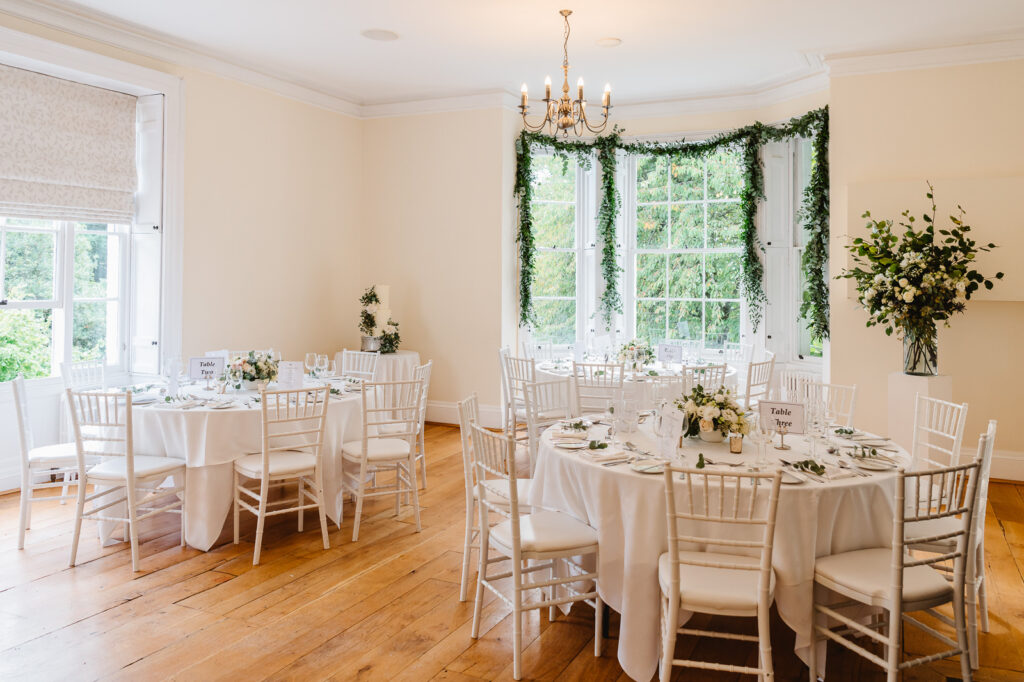 Brightly decorated wedding reception with white tables and chairs set for a celebration.