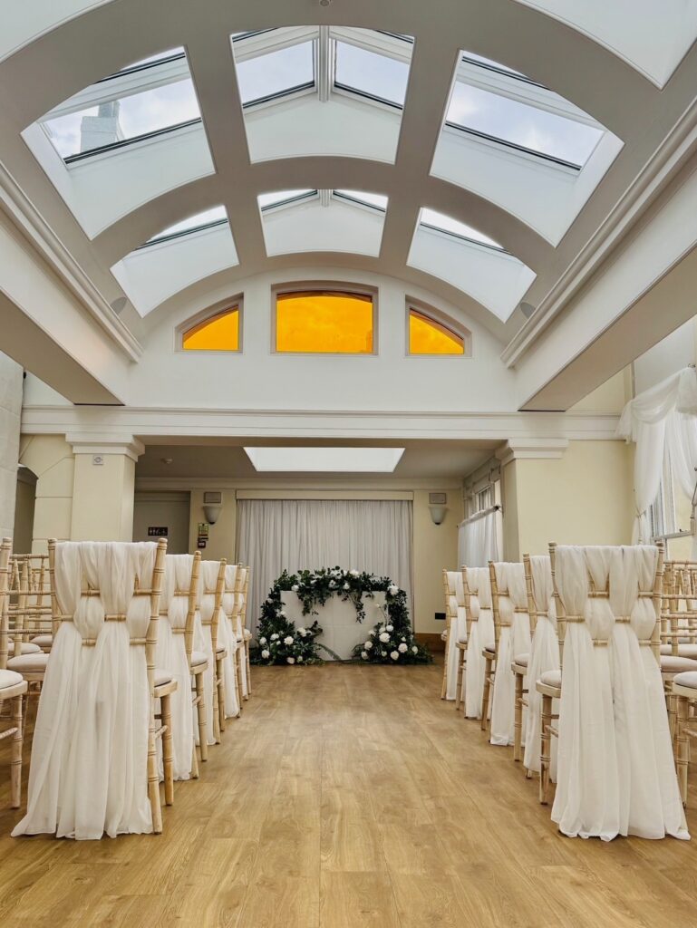 Rows of chairs with white material in a long white room.