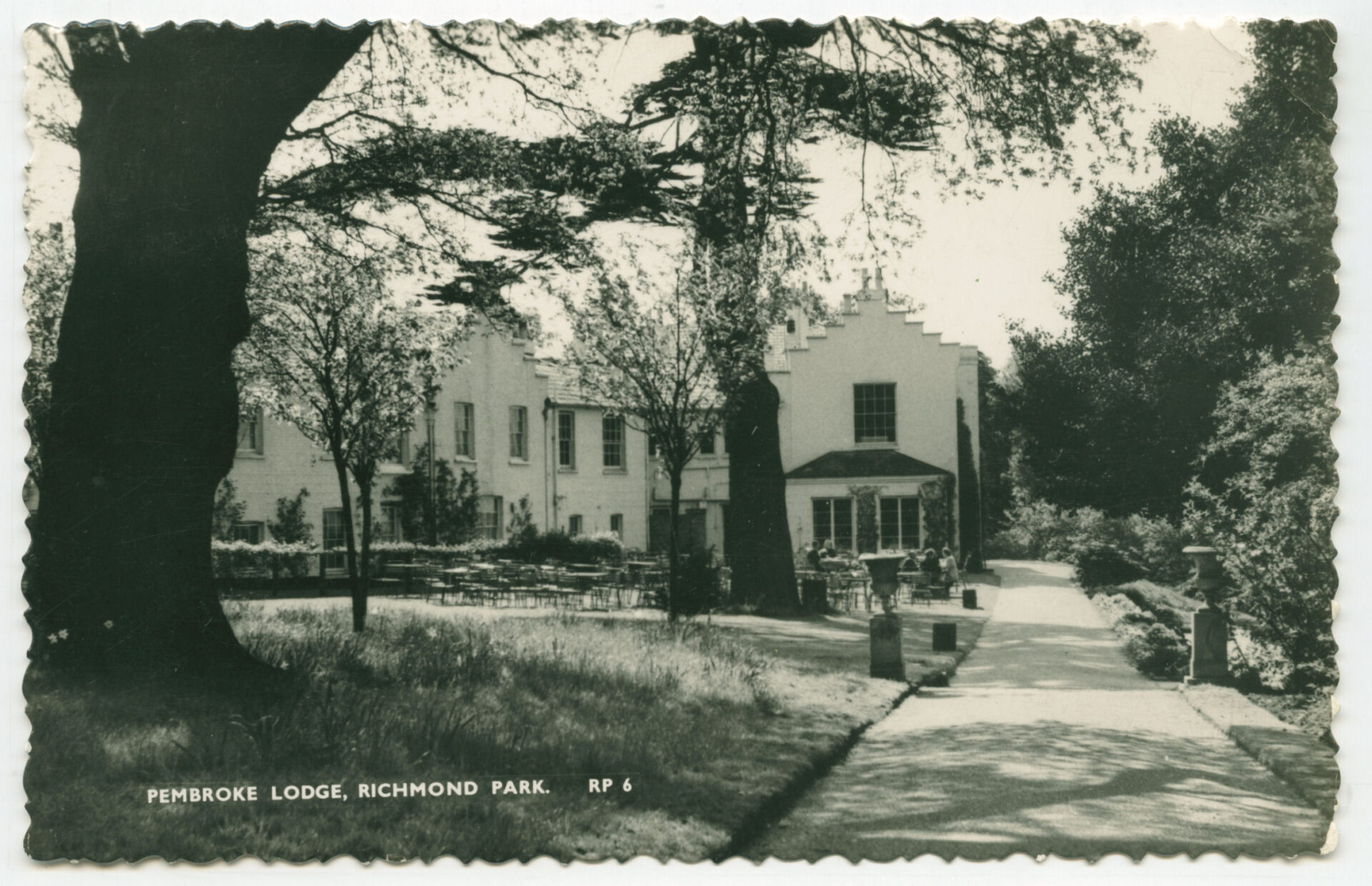 1960s hstoric black and white postcard of Pembroke Lodge, highlighting the elegant house amidst a backdrop of trees in Richmond Park.